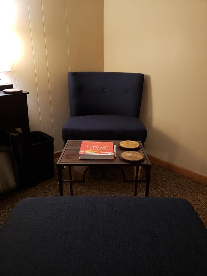 A navy armchair and small table where sessions begin with conversation